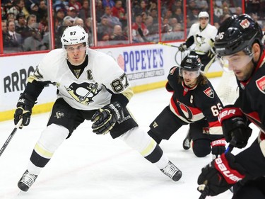 Sidney Crosby of the Pittsburgh Penguins in the offensive zone against Erik Karlsson (65) and Clarke MacArthur (R)  of the Ottawa Senators during second period of NHL action at Canadian Tire Centre in Ottawa, February 12, 2015.