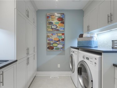 The oversize laundry room is packed with cabinets, both above the washer and dryer and surrounding the handy sink.