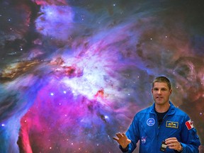 Canadian stronaut Jeremy Hansen in front of photo of the Orion Nebula behind him while announcing an additional $2.6 million being invested by Canada in the James Webb Space Telescope project.