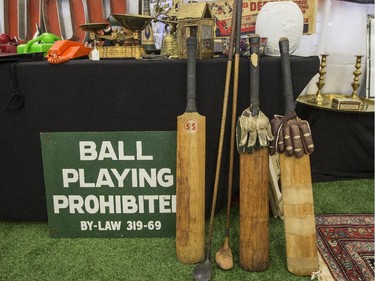 Cricket bats and golf clubs beside a sign prohibiting Ball Playing games. Ottawa Antique and Vintage Market at the Carleton University Fieldhouse.