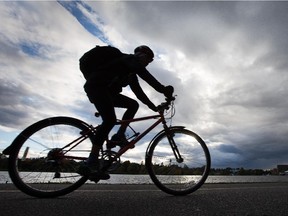 A cyclist rides along Dow's Lake under cloudy skies.