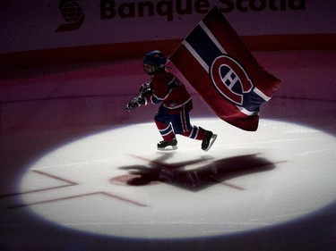 A young hockey player skates with the Montreal Canadiens flag during pre-game ceremonies.