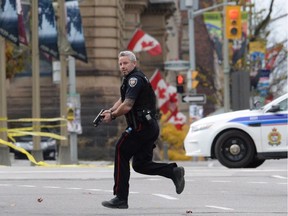 An Ottawa police officer runs with his weapon drawn in Ottawa on Wednesday Oct.22, 2014.