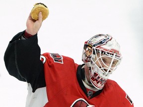 Ottawa Senators' Andrew Hammond, nicknamed 'The Hamburglar' holds up a hamburger after it was thrown on the ice after he defeated the Philadelphia Flyers 2-1 in the shootout in NHL hockey action in Ottawa on Sunday, March 15, 2015.