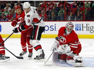 Carolina Hurricanes goalie Anton Khudobin (31) of Kazakhstan, blocks a shot as Hurricanes' John-Michael Liles (26) battles with Ottawa Senators' Milan Michalek (9) during the first period.