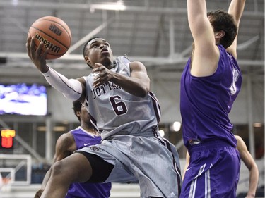 Bishop's Gaiters' Caleb Agada (6) drives to the basket as Ottawa Gee Gees' Mike Andrews defends during first half CIS Final Eight basketball action in Toronto on Thursday, March 12, 2015.