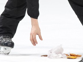 A member of the Canadian Tire Centre ice crew picks up a hamburger that was tossed onto the ice after the Ottawa Senators defeated the Boston Bruins on March 19.