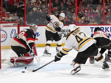 Andrew Hammond #30 of the Ottawa Senators makes a pad save against Torey Krug #47 of the Boston Bruins after receiving a pass from team mate Loui Eriksson #21.