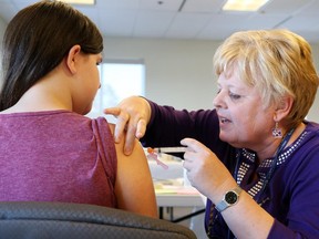 Brianna Grant receives a vaccine from Renée Larocque during an Ottawa Public Health catch up vaccination clinic, March 11, 2015.   (Jean Levac/ Ottawa Citizen)