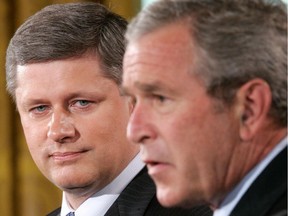 U.S. President George W. Bush (R) speaks as Canadian Prime Minister Stephen Harper (L) looks on during a joint news conference July 6, 2006 at the East Room of the White House in Washington, DC. This was the first visit of Harper to Washington since he took office in January.