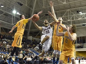 Carleton Ravens' Philip Scrubb (23) shoots as Victoria Vikes' Grant Sitton (0), Reiner Theil (4) and Chris McLaughlin (12) defend to during second half CIS basketball action in Toronto on Saturday, March 14, 2015.