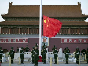 Files: Chinese paramilitary policemen perform a flag-lowering ceremony near a portrait of Mao Zedong on Tiananmen Gate in Beijing, Monday, March 9, 2015.