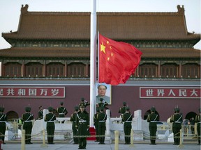 Chinese paramilitary policemen perform a flag-lowering ceremony near a portrait of Mao Zedong on Tiananmen Gate in Beijing, Monday, March 9, 2015. Thousands of delegates from across the country are in the Chinese capital this week to attend the Chinese People's Political Consultative Conference and the National People's Congress.