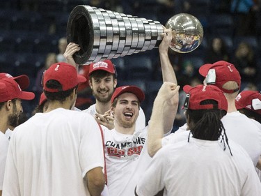 Carleton Ravens' Connor Wood raises the trophy as he celebrates with teammates after defeating the Ottawa Gee-Gees to win the CIS basketball final in Toronto on Sunday March 15, 2015.