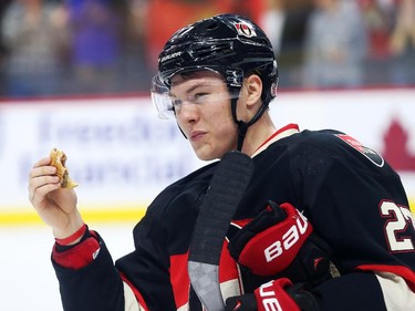 Curtis Lazar of the Ottawa Senators eats a burger that was thrown on the ice after his team's beat the Boston Bruins at Canadian Tire Centre in Ottawa, March 19, 2015.   (Jean Levac/ Ottawa Citizen)