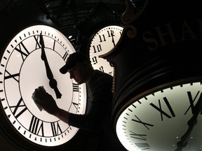 Dave LeMote wipes down a post clock at Electric Time Company, Inc. in Medfield, Mass., Friday, March 7, 2014. Most Americans will set their clocks 60 minutes forward before heading to bed Saturday night, but daylight saving time officially starts Sunday at 2 a.m. local time (0700GMT). (AP Photo/Elise Amendola)