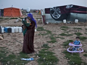 In this Sunday, March 8, 2015 photo, Syrian refugee Rifaa Ahmad, 50, cuddles her granddaughter at an informal tented settlement near the Syrian border, on the outskirts of Mafraq, Jordan.