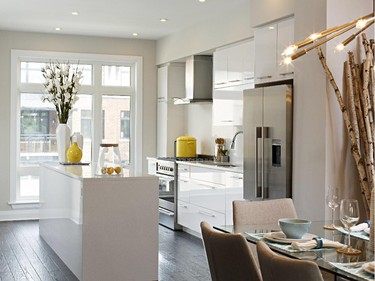 In the Jericho townhome, the kitchen — gleaming white lacquer Euro cabinetry, glass and steel range hood — is pulled to the front of the home.