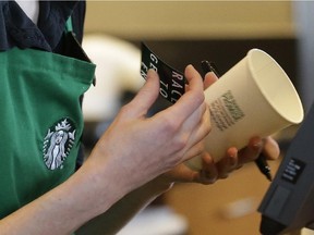 Holly Ainslie, a barista at a Starbucks store in Seattle puts a "Race Together" sticker on a customer's cup, Wednesday, March 18, 2015. Starbucks CEO Howard Schultz announced earlier in the day at the company's annual shareholder meeting that participating baristas at stores in the U.S. will be putting the stickers on cups and also writing the words "#RaceTogether" for customers in an effort to raise awareness and discussion of race relations.