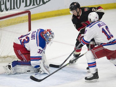 New York Rangers goalie Cam Talbot, left, deflects a shot from Ottawa Senators right wing Curtis Lazar, centre, as he is pressured by Ranger centre J.T. Miller during first period NHL hockey action.