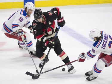 Ottawa Senators centre Kyle Turris tries to stick handle the puck between New York Rangers centre J.T. Miller, left, and right wing Mats Zuccarello, right, during first period NHL hockey action.