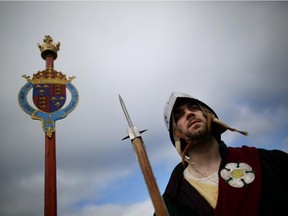 A  member of a re-enactment group dressed as a 'Gate Guard' stands next to The Royal Arms of King Richard III at Bosworth Battlefield Heritage Centre on March 22, 2015 near Leicester, England.