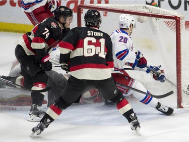 New York Rangers left wing Chris Kreider, right, scores on a bouncing puck under pressure from Ottawa Senators defenceman Mark Borowiecki, left, and right wing Mark Stone during first period NHL hockey action.
