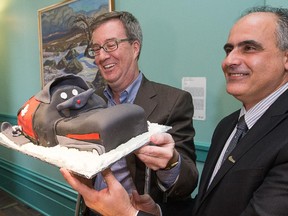Mayor Jim Watson, seen here with Coun. George Darouze, makes his return to Ottawa city hall following a snow mobile accident on Feb. 28, when he fractured his pelvis. He was presented with a cake in the shape of a snowmobile.