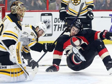 Mika Zibanejad of the Ottawa Senators is tripped by Dougie Hamilton of the Boston Bruins as goalie Tuukka Rask looks on during first period NHL action.
