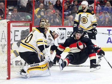 Mika Zibanejad of the Ottawa Senators is tripped by Dougie Hamilton of the Boston Bruins as goalie Tuukka Rask looks on during first period NHL action.