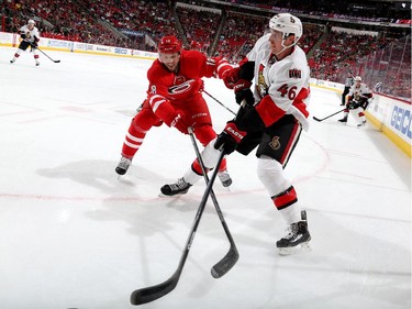 Jay McClement #18 of the Carolina Hurricanes reaches to poke the puck away from Patrick Wiercioch #46 of the Ottawa Senators.