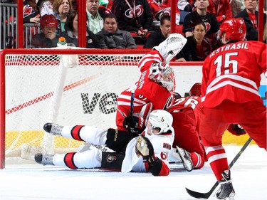 Mark Stone #61 of the Ottawa Senators goes down in front of the net with John-Michael Liles #26 of the Carolina Hurricanes as Anton Khudobin #30 makes a save.