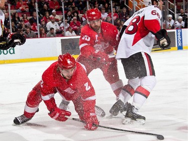 Brendan Smith #2 and Henrik Zetterberg #40 of the Detroit Red Wings battle for the puck with Mike Hoffman #68 of the Ottawa Senators.