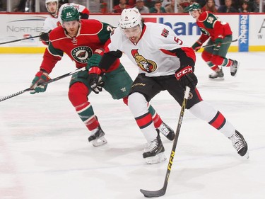 Cody Ceci #5 of the Ottawa Senators skates with the puck while Kyle Brodziak #21 of the Minnesota Wild defends.