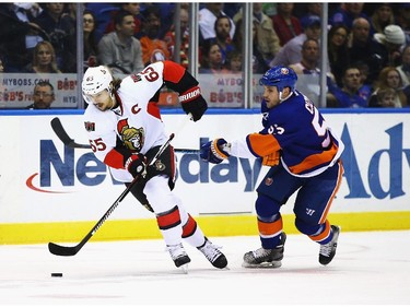 Erik Karlsson #65 of the Ottawa Senators skates with the puck against Casey Cizikas #53 of the New York Islanders.