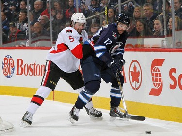 Drew Stafford #12 of the Winnipeg Jets plays the puck behind the net as Cody Ceci #5 of the Ottawa Senators defends during first period action.