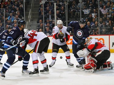 Dustin Byfuglien #33, Adam Lowry #17 of the Winnipeg Jets, Cody Ceci #5 and goaltender Andrew Hammond #30 of the Ottawa Senators keep an eye on the loose puck during first period action.