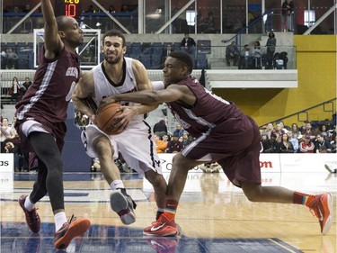 Carleton Ravens' Philip Scrubb (centre right) drives at Ottawa Gee-Gees' Gabriel Gonthier-Dubue (left) Johnny Berhanemeskel (centre left) and Caleb Agada during second half CIS basketball final action in Toronto on Sunday, March 15, 2015.