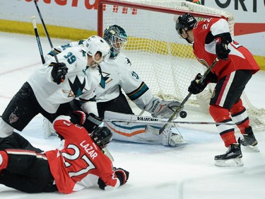 San Jose Sharks goaltender Antti Niemi makes a glove save as Ottawa Senators' Eric Condra (22) and Curtiz Lazar (27) look on while Sharks' Logan Couture (39) defends during second period NHL action.