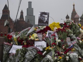 Signs reading "propaganda kills!" and "Fight!" are seen with his portraits and flowers placed at the site where Boris Nemtsov, a charismatic Russian opposition leader and sharp critic of President Vladimir Putin, was gunned down on Friday, Feb. 27, 2015 near the Kremlin against a backdrop of St. Basil's Cathedral in Moscow, Russia, Monday, March 2, 2015. N