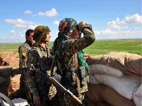 Members of the Kurdish People's Protection Units (YPG) monitor the positions of Islamic State (IS) group in the Syrian town of Ras al-Ain, close to the Turkish border on March 13, 2015.