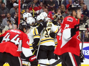 The Boston Bruins celebrate their first goal against Jean Gabriel Pageau, left, and Mark Borowiecki of the Ottawa Senators during second period NHL action.