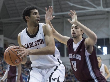 Carleton Ravens' Thomas Scrubb (left) looks to pass while being covered by Ottawa Gee-Gees' Matt Plunkett during first half CIS basketball final action in Toronto on Sunday, March 15, 2015.