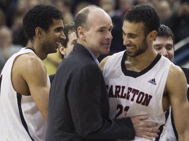 Carleton Ravens' Head Coach Dave Smart (centre) congratulates Philip Scrubb (right) as Thomas Scrubb walks past as they celebrate defeating the Ottawa Gee-Gees' to win the CIS basketball final in Toronto on Sunday March 15, 2015.