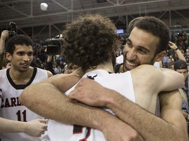Carleton Ravens' Philip Scrubb (centre right) hugs Gavin Resch as Thomas Scrubb (left) looks on as the Ravens celebrate after defeating the Ottawa Gee-Gees to win the CIS basketball final in Toronto on Sunday March 15 , 2015.