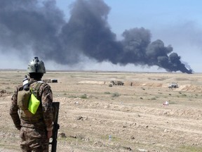 TOPSHOTS An Iraqi security forces member stands looking at smoke billowing from the Ajeel oil field located 35km (22 miles) northeast of Tikrit on March 11, 2015 after it was reportedly set on fire by the Islamic State jihadist (IS) group to provide cover from air strikes during the military operation by Iraqi pro-government forces to retake the city. AFP PHOTO / WILLIAM G. DUNLOP  William Dunlop/AFP/Getty Images
