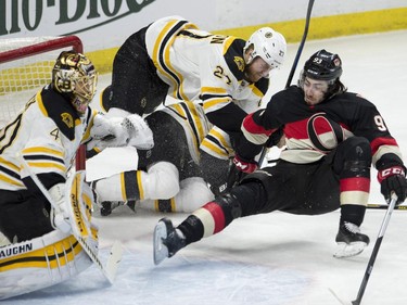 Boston Bruins defenseman Dougie Hamilton (27) collides with Ottawa Senators center Mika Zibanejad and a teammate in front of goalie Tuukka Rask during first period NHL action.