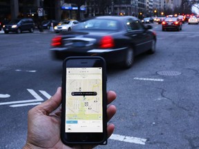 An UBER application is shown as cars drive by in Washington, DC on March 25, 2015. Uber said it was ramping up safety in response to rape allegations against a driver in India and growing concerns about background checks for operators of the popular ride-sharing service. In other cities where Uber operates, critics had complained that a lack of licensing and background checks of drivers could imperil those who use the service.