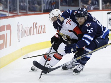 Winnipeg Jets' Mark Scheifele (55) and Ottawa Senators' Mark Borowiecki (74) fight for possession behind the Sens' net during second period NHL action.