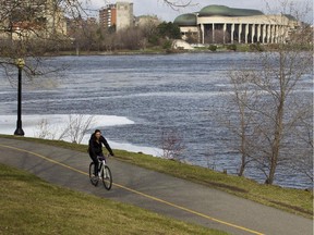 A cyclist rides a path behind Parliament Hill beside the Ottawa River. Everyone supports the motives behind the Ottawa River Action Plan, but the devil may be in the details, writes Joanne Chianello.